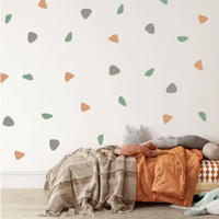 Scattered triangular and teardrop shapes in orange, grey, and green on a wall.